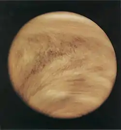 Light brown clouds wrap around a planet, as seen from space.