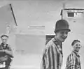 Liberated Jewish prisoners - one wearing a German Stahlhelm - smiling for the camera