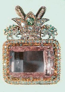 A large rectangular pink multifaceted gemstone, set in a decorative surround.